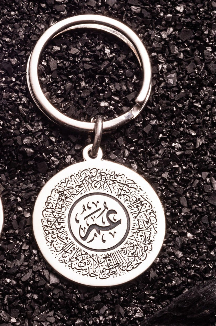 Silver keychain with a circular pendant on a dark textured background
